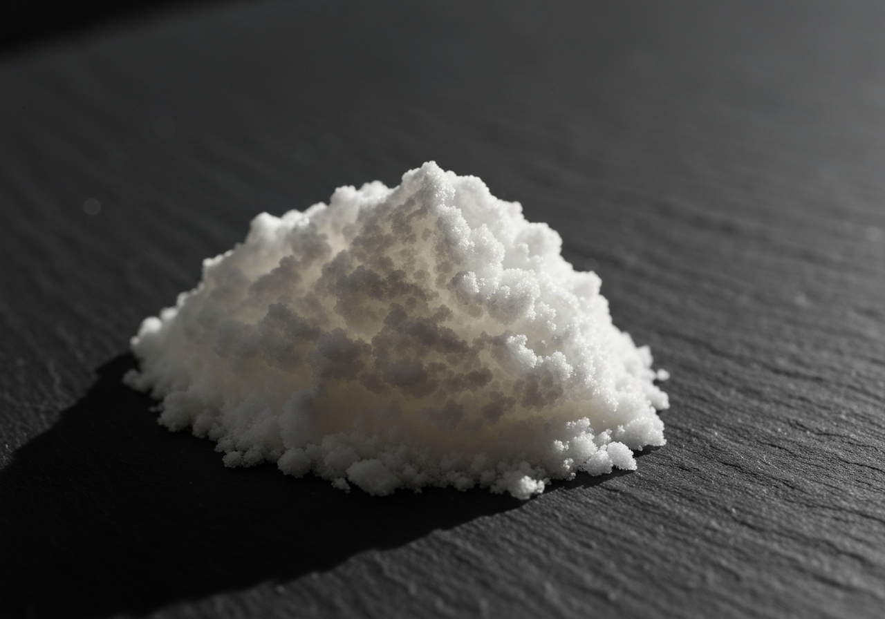 Kyselina askorbová: Čistí opravdu tělo? (Pravda) 2 A macro, high-detail editorial photograph of a pure white crystalline powder of L-ascorbic acid on a dark slate background, side-lit with soft natural light, minimalist scientific aesthetic, 85mm lens, no text, no letters.