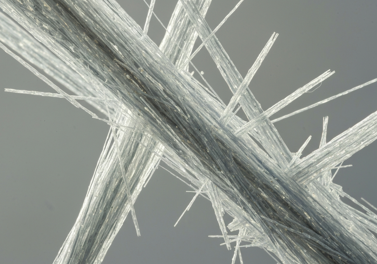 Macro photography of fibrous mineral structures, microscopic view of silicate mineral fibers, neutral industrial background, editorial photography, soft natural light, 85mm lens, highly detailed, no text, no letters