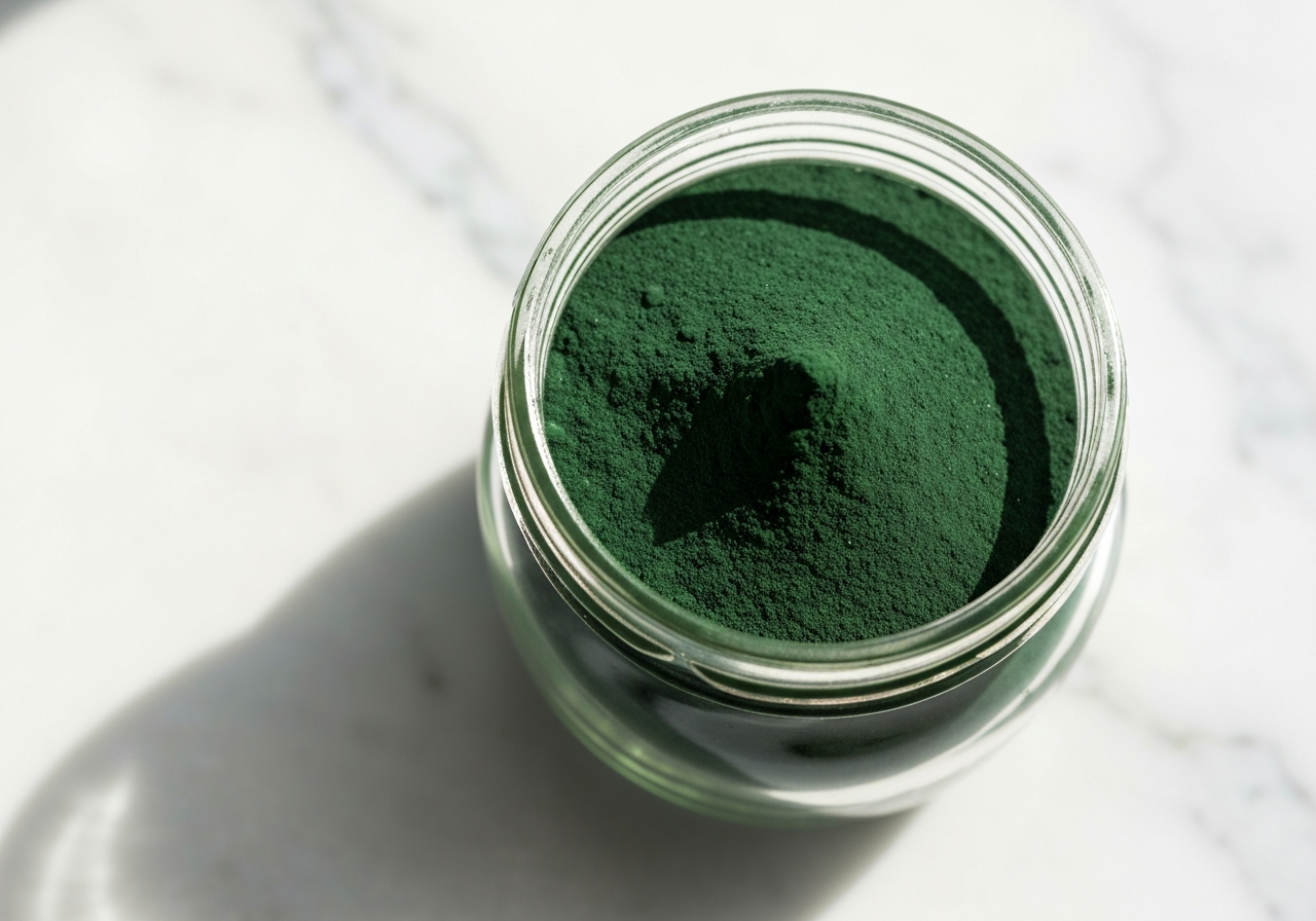 A professional laboratory glass jar filled with vibrant green spirulina powder, placed on a clean white marble surface, macro photography, soft natural morning light, depth of field, high-end editorial wellness aesthetic, no text, no words, no letters.